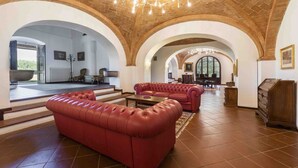 A spacious lobby with red leather sofas, a chandelier, and arched ceilings.