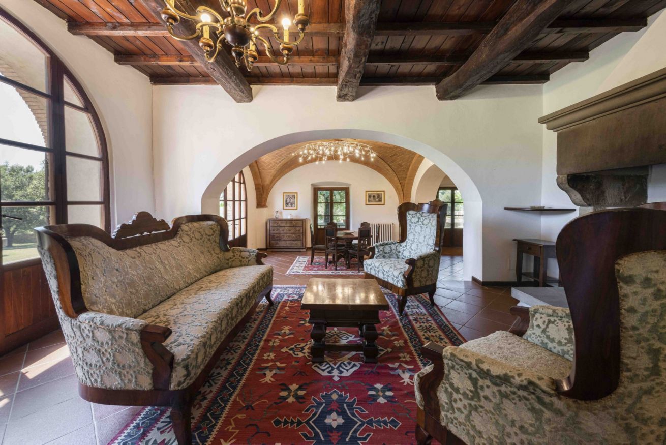 Una habitación amplia con techo de madera, un gran arco de entrada y un conjunto de sofá tradicional.