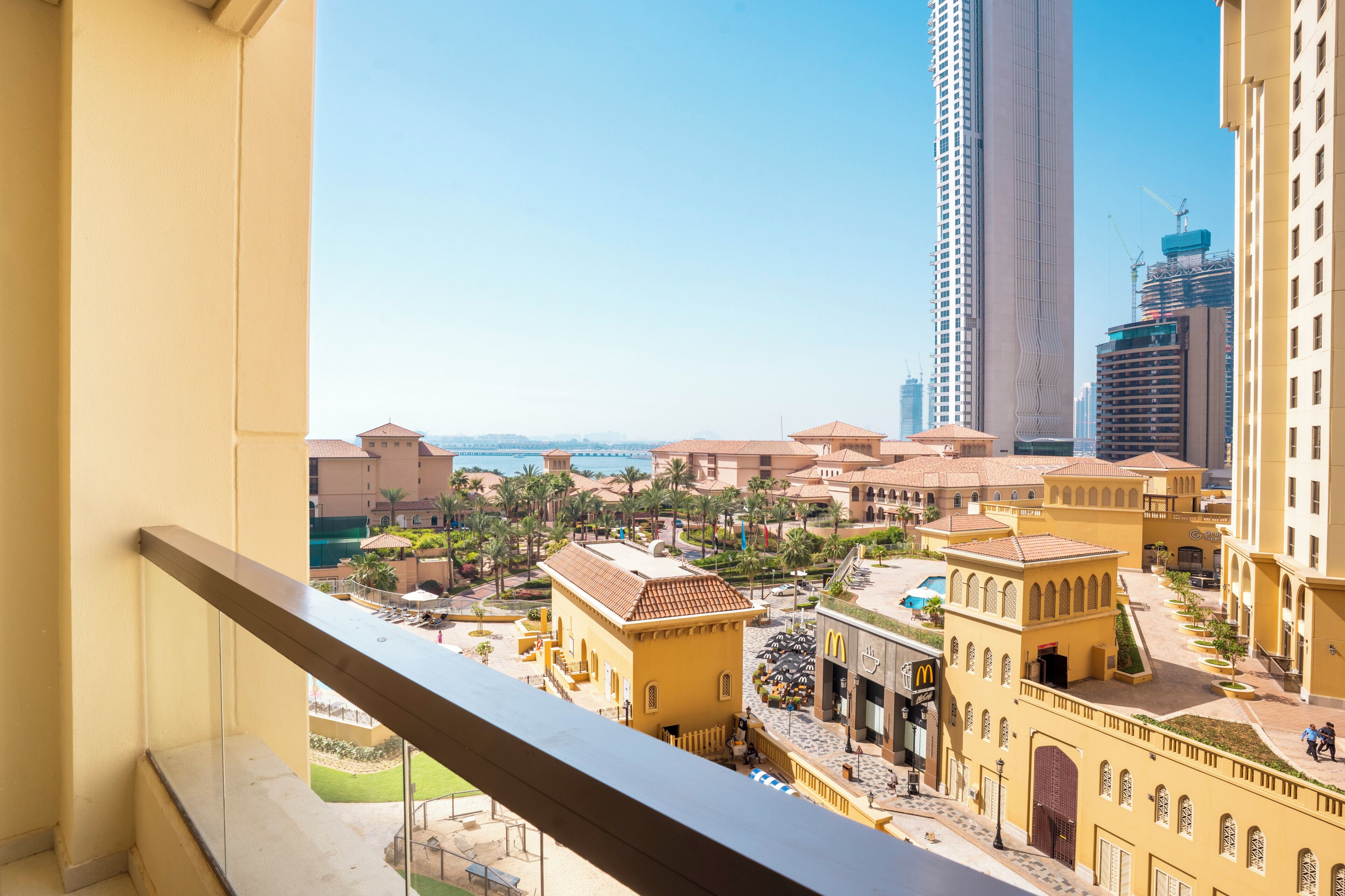 A high-rise hotel with balconies, a pool, and a view of a cityscape.