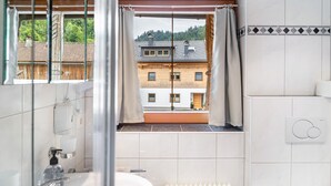 Un baño con ventana, un radiador y vistas a un edificio.