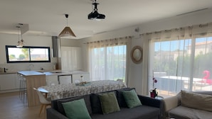 Una sala de estar moderna con un sofá gris, una mesa de centro de madera y un comedor con una cocina al fondo.