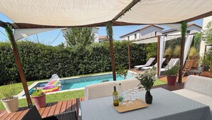 Un patio exterior con piscina, terraza de madera y zona de estar.