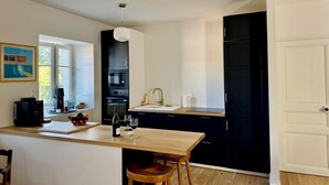 A modern kitchen with dark cabinets, a wooden island, and a black refrigerator.