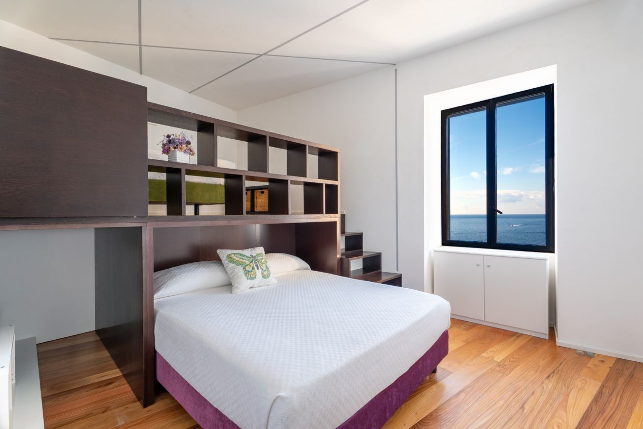 Um quarto moderno com cama, estantes embutidas, janela com vista e radiador.