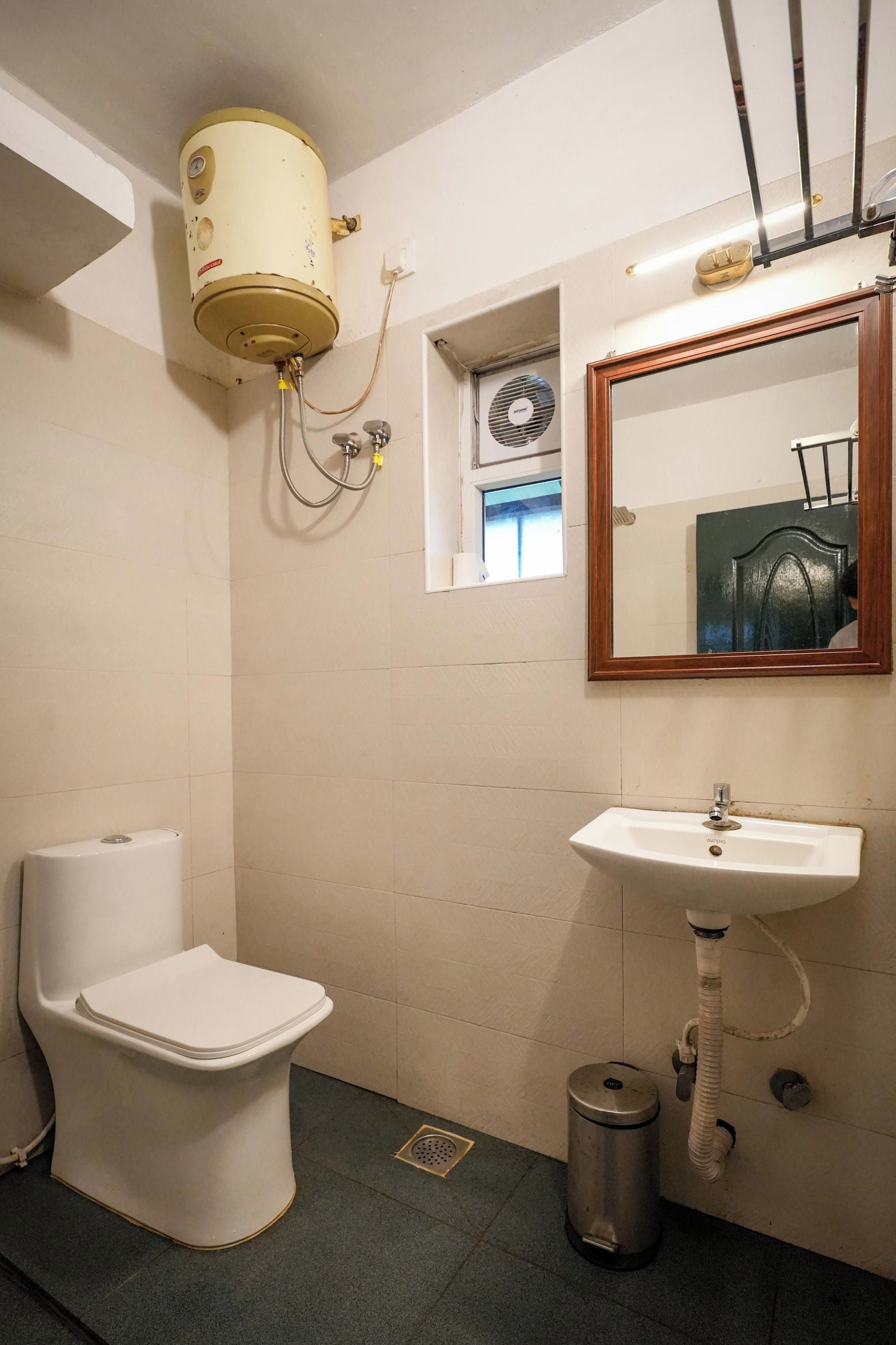 A bathroom with a toilet, sink, and a mirror.