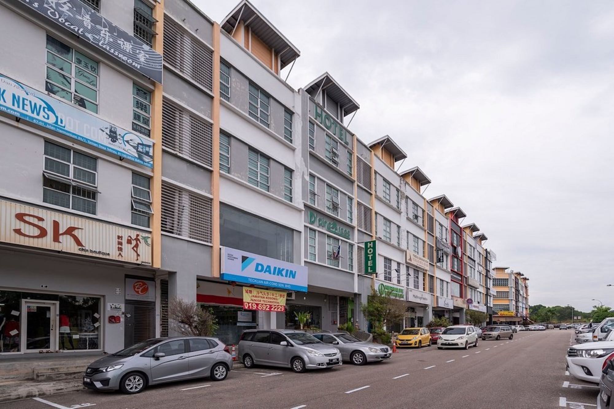 A multi-story hotel with various shops on the ground floor, including a visible 'Dakin' sign.