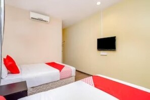 Una habitación de hotel con dos camas, un televisor montado en la pared y un equipo de aire acondicionado.