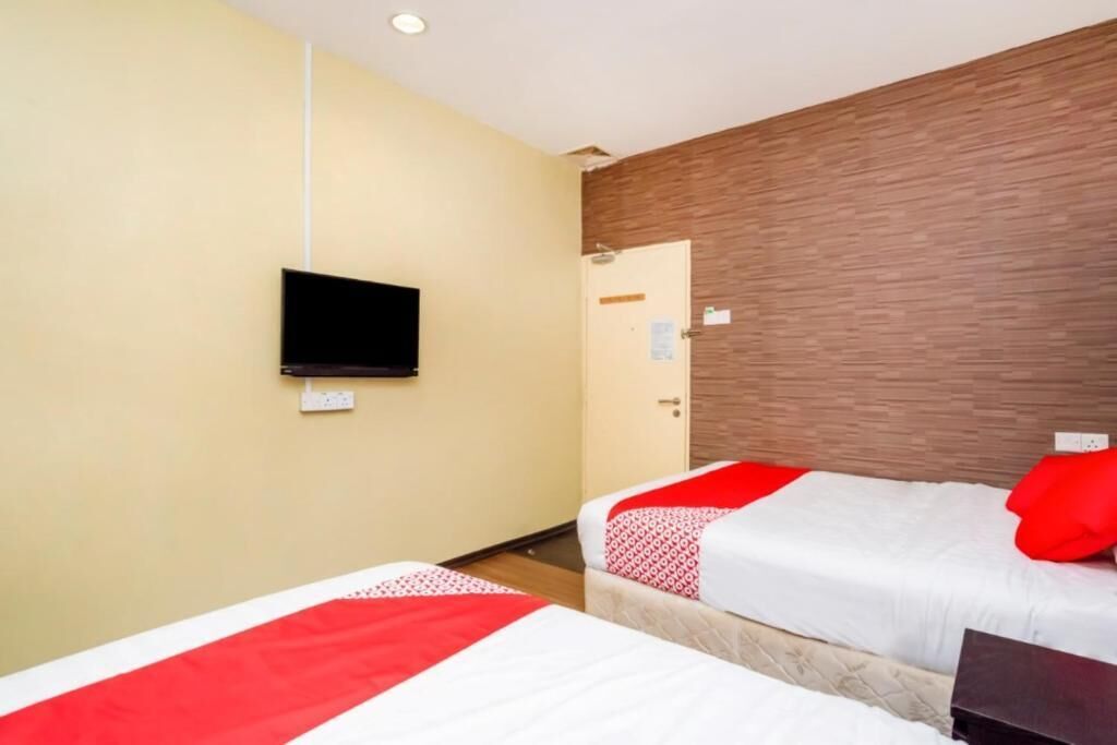 A hotel room with two beds, a flat-screen TV mounted on the wall, and a wooden accent wall.