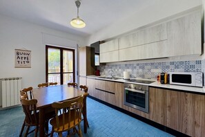 Una cocina moderna con armarios de madera, una mesa de comedor con sillas, un microondas y una tetera.