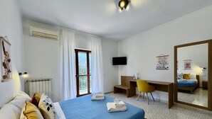 Une chambre d’hôtel avec un lit, un bureau, une chaise, une télévision et un grand miroir.