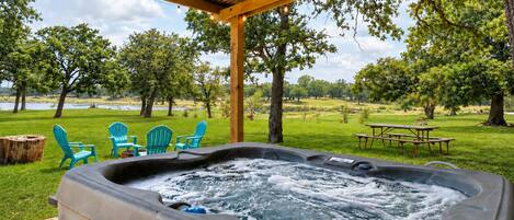 Un jacuzzi con vistas a un área verde, árboles y una masa de agua.