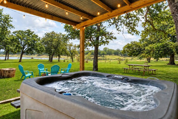 Un jacuzzi con vistas a un área verde, árboles y una masa de agua.