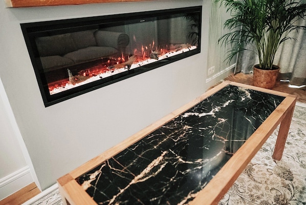 Suite, vista a la ciudad | Área de sala de estar | Smart TV de 65 pulgadas con canales por cable y chimenea 