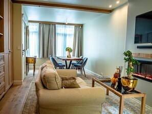 A living room with a sofa, a coffee table, and a dining area with chairs and a table. - The Lovelace Residence (Bruges)