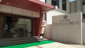 The entrance of Hotel Fortune Blue with a green carpet leading to the door, a staircase, and a glass facade. - HOTEL FORTUNE BLUE (Sikar)