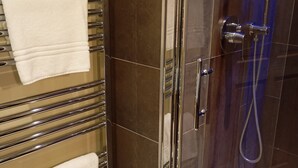 Een moderne badkamer met een douche met glazen wand, chroomhanddoekrekken en een handdouche.