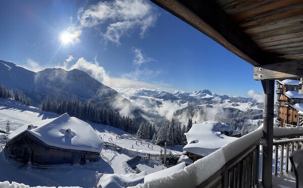 A snow-covered mountain landscape with a wooden cabin and a building with a balcony.