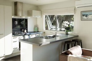Una cocina moderna con una isla central, un ventanal con vistas a zonas verdes y una estufa integrada.