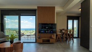 Un salon moderne doté d’un grand téléviseur à écran plat, d’un coin repas et offrant une vue sur l’océan.