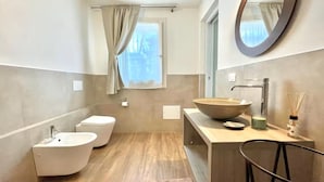 Une salle de bain moderne avec une baignoire sur pieds, un lavabo à large cuve et un miroir au-dessus du lavabo.