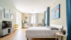Une chambre d’hôtel moderne équipée d’un grand lit, d’un bureau, d’une télévision et d’une fenêtre avec des rideaux.