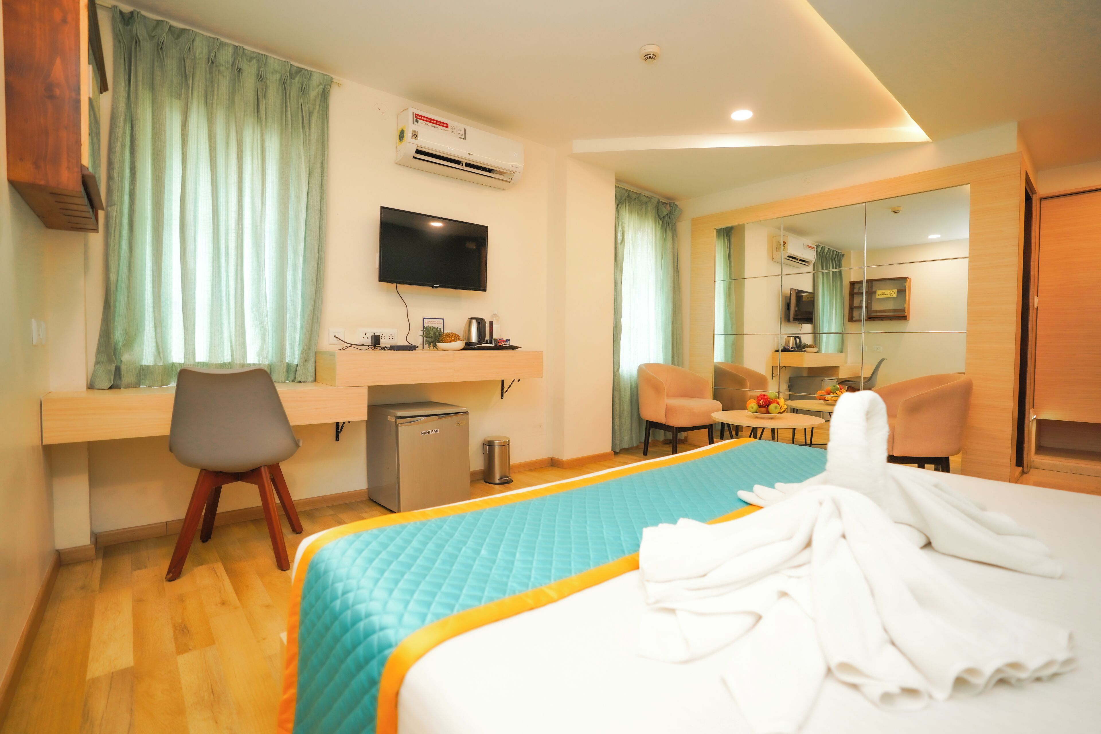 Ein Hotelzimmer mit Bett, Schreibtisch, Stuhl, Fernseher und einer kleinen Küchenzeile.