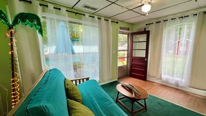 Quarto com sofá verde-água, uma pequena mesa de madeira e parede verde.