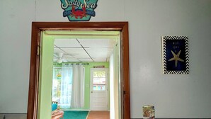 Um quarto com carpete verde, porta de madeira, um letreiro com a inscrição 'Salty Sea Crab Shack' e uma parede decorada com uma estrela-do-mar.