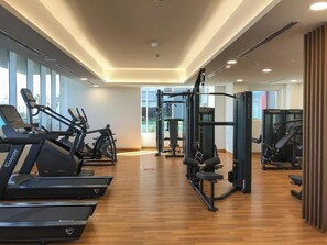 A gym with treadmills, a squat rack, and weight machines. - Bloomfields Spacious 1BR Bloom Tower  (Dubai)