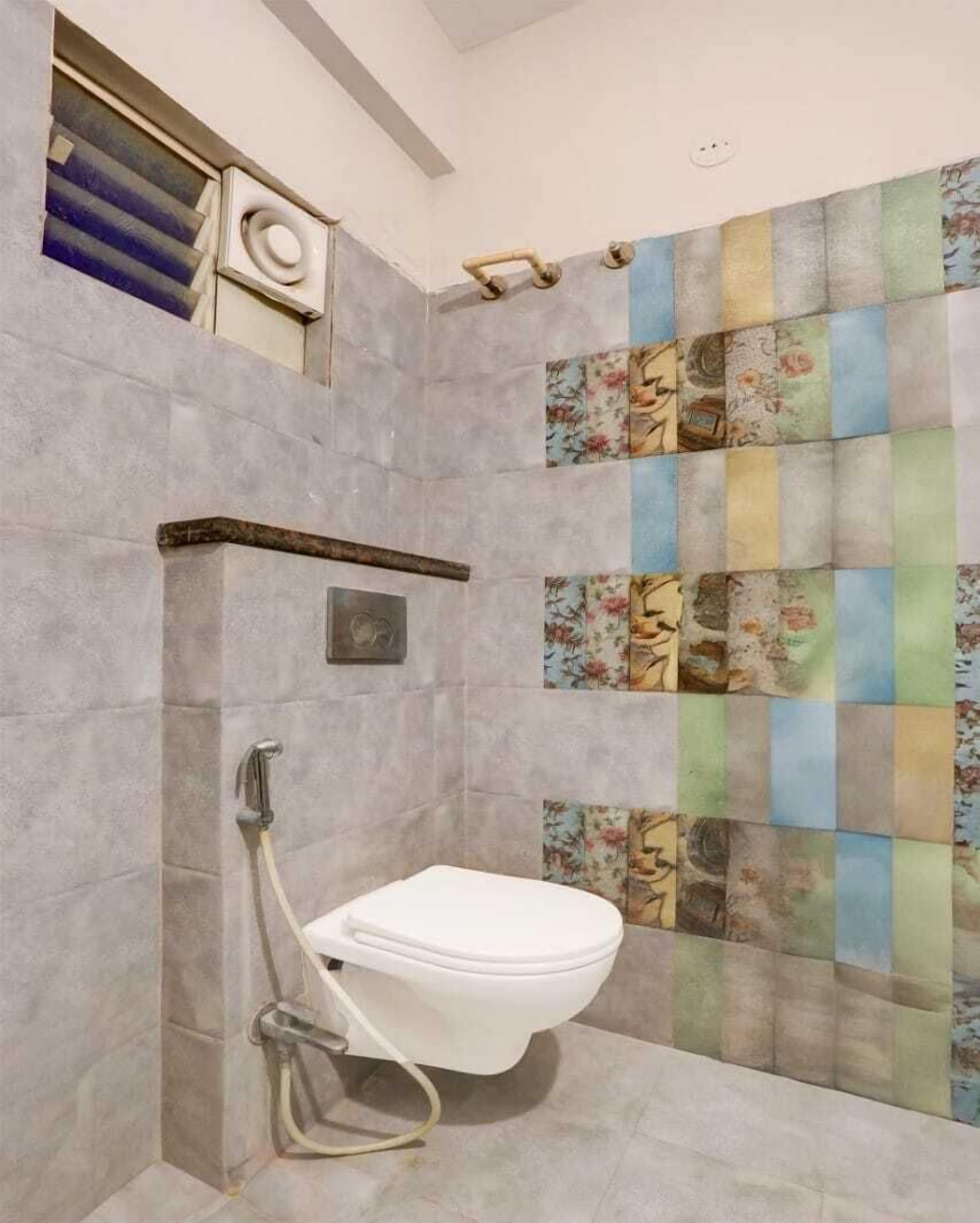 A bathroom with a white toilet, a shower area, and a tiled wall with a floral pattern.