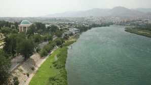 Une rivière bordée d’un parc et, sur la gauche, un bâtiment surmonté d’un dôme.