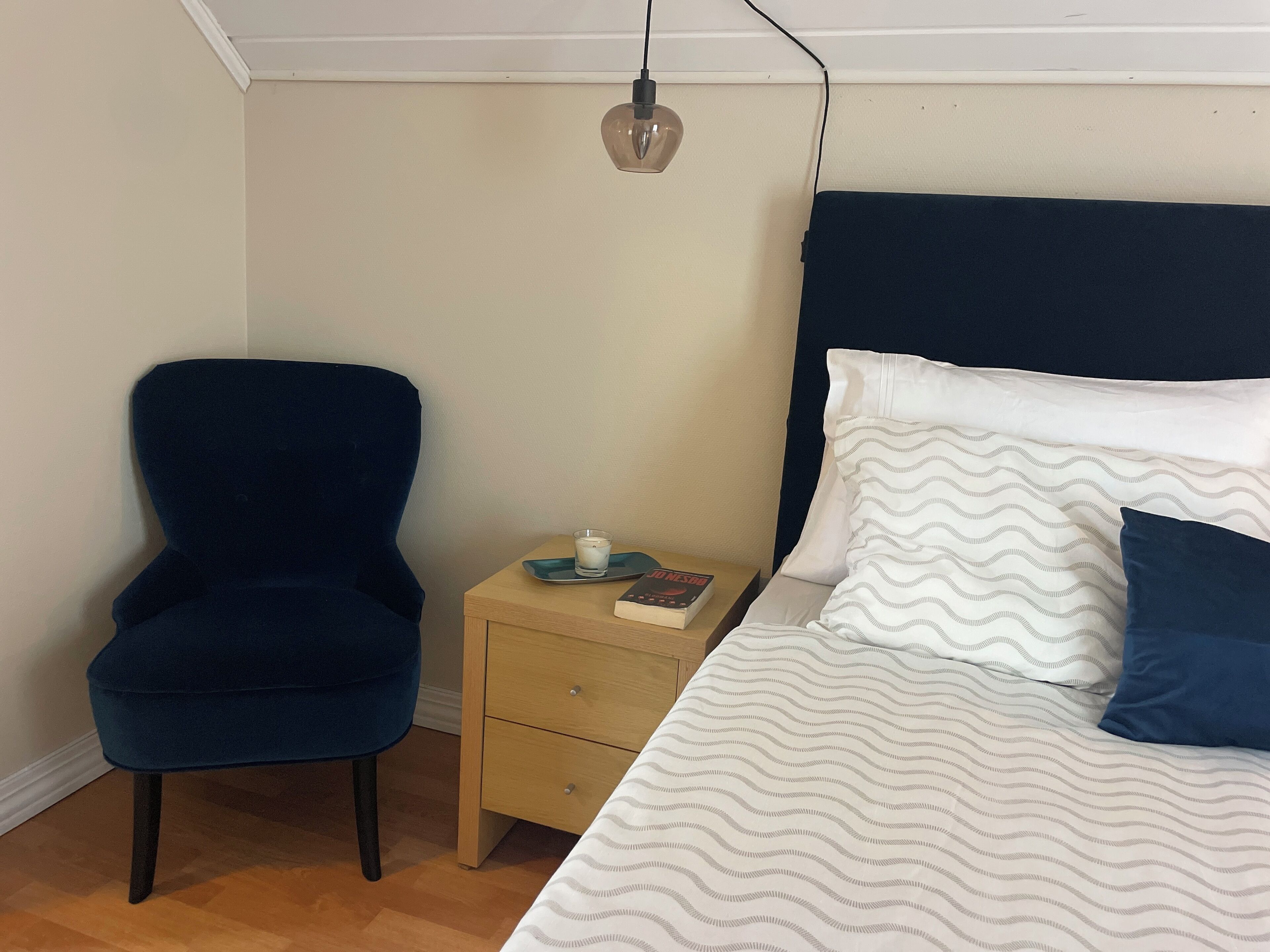 Une chambre à coucher avec un lit, une chaise, une table de chevet et une lampe.