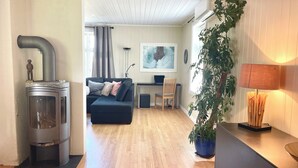 Een moderne woonkamer met een open haard, een bank, een bureau en een potplant.