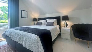 Een moderne slaapkamer met een groot bed, twee nachtkastjes, een stoel en een hanglamp.