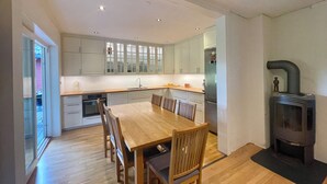 Een moderne keuken met een eetgedeelte, houten vloeren en een ingebouwde houtkachel.