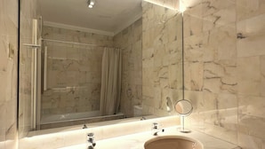 Een badkamer met twee wastafels, een grote spiegel en marmeren wanden.