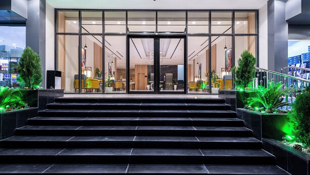 A modern hotel entrance with glass doors, a staircase leading up, and indoor plants. - Al Qasr Hotel Taif (Taif)