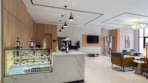 A modern hotel lobby with a marble reception desk, a beverage display, seating area, and a large TV screen. - Al Qasr Hotel Taif (Taif)