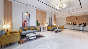 A modern living area with sofas, a coffee table, and a kitchen area with bar stools. - Al Qasr Hotel Taif (Taif)