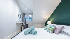 Et hotelværelse med en seng, et vindue med gardiner, et spejl og en radiator.