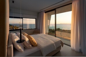 Ein modernes Schlafzimmer mit einem großen Bett, Meerblick und einem Balkon.