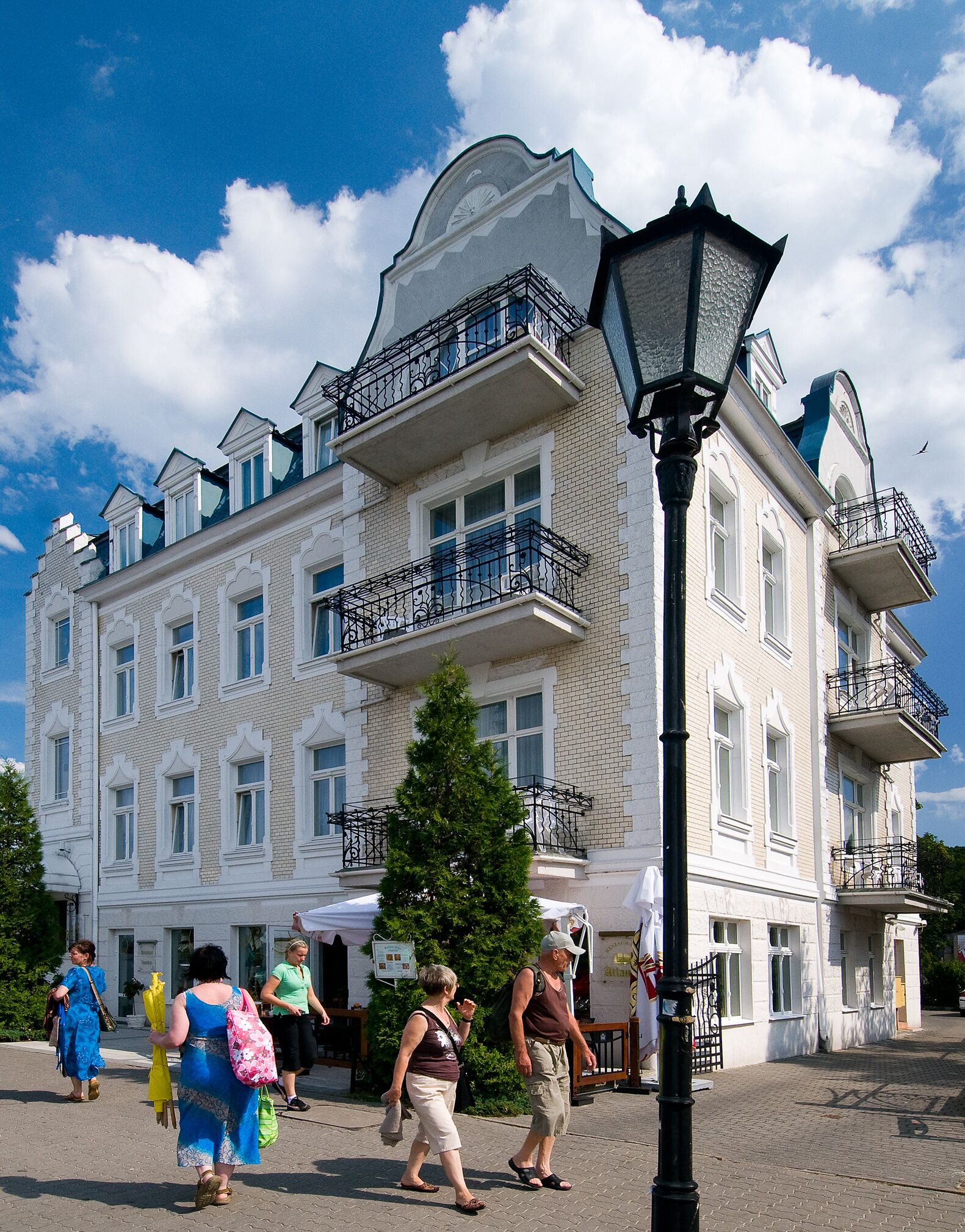 A multi-story building with balconies, a Christmas tree, and a street lamp.