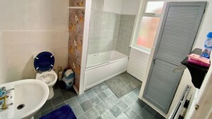 Un baño con inodoro, lavamanos, ducha y toallero.