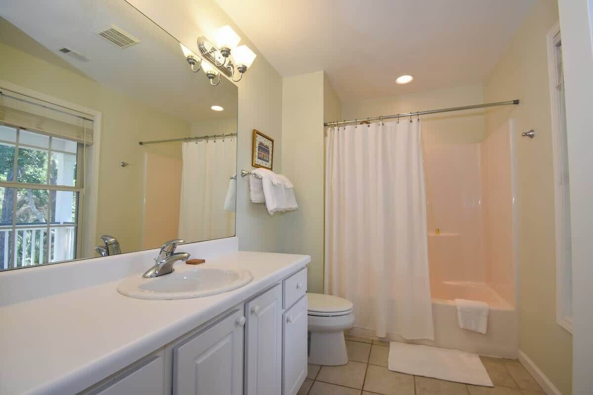 A bathroom with a sink, toilet, shower, and a large mirror.