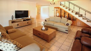 Ein Wohnzimmer mit einer Couch, einem Couchtisch, einem Fernseher und einer Treppe.