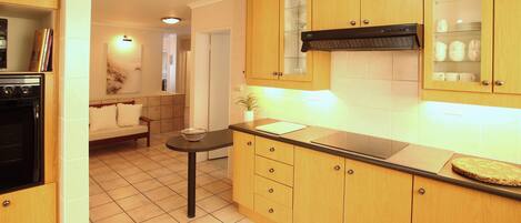 A modern kitchen with wooden cabinets, a black countertop, and a built-in stove.