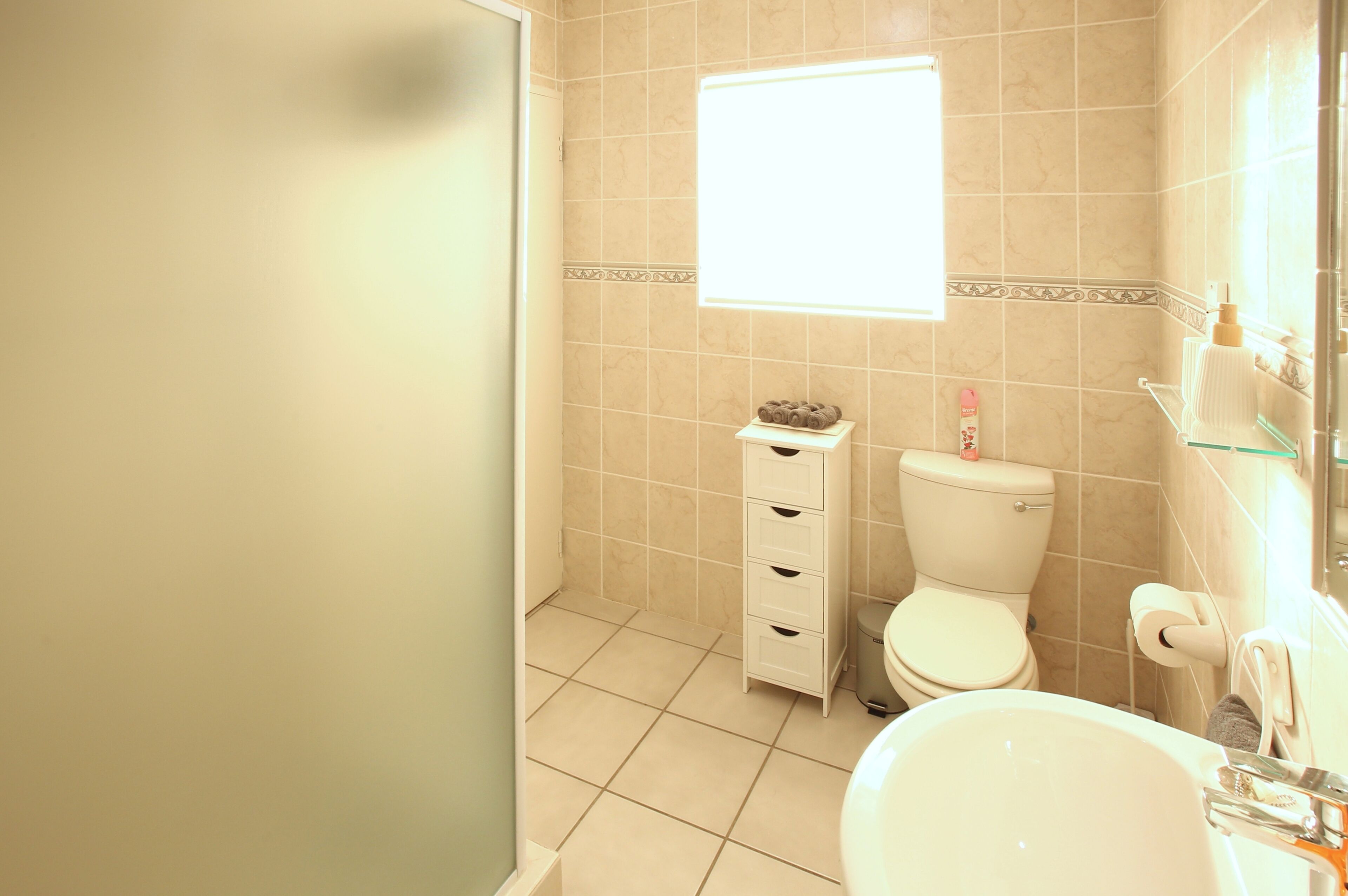A bathroom with a toilet, sink, and a small window.