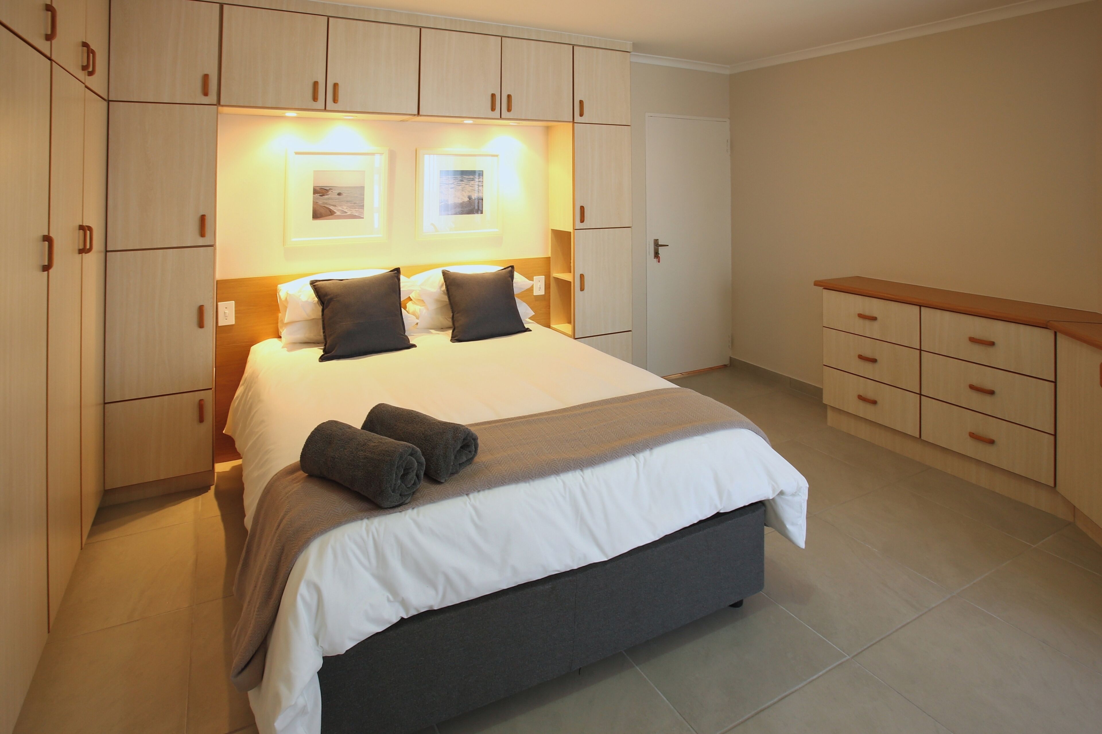 A well-lit bedroom with a large bed, built-in wardrobe, and bedside tables.