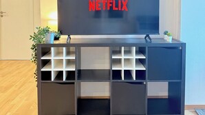 A modern living room with a large flat-screen TV mounted on a black entertainment unit. - Modern Flat | washing machine, underfloor heating, rain shower (karlsruhe)