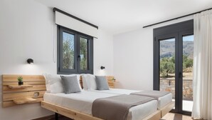 A modern bedroom with a wooden bed, two bedside tables, a nightstand, a window, and a view of the outdoors. - Kourtaliotis Villa Crete (Agios Vasileios)